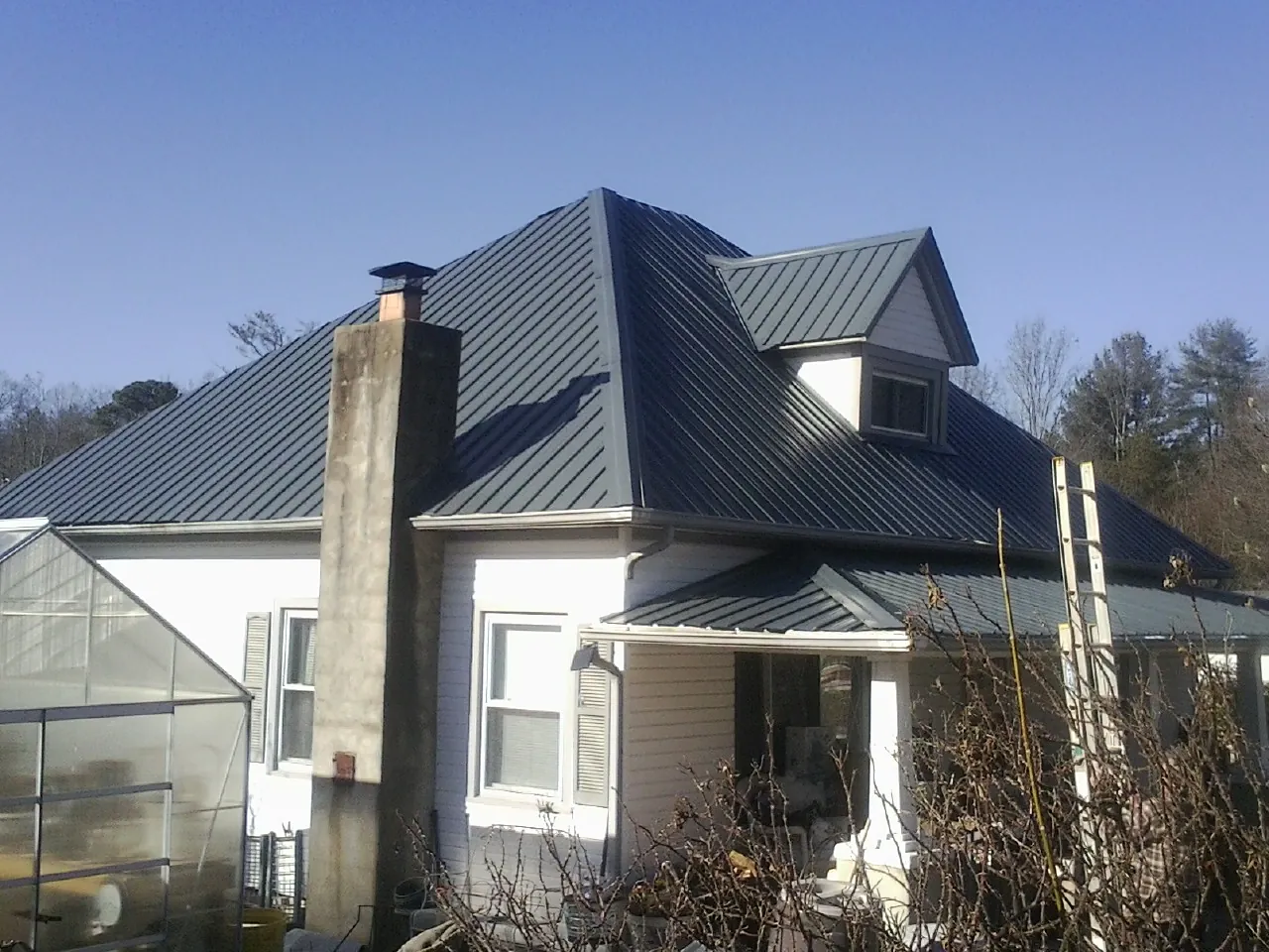 Dark blue standing seam metal roof on a white farmhouse with dormer — Slate & Tile Roof Repair by Roofing Brothers in Arcanum