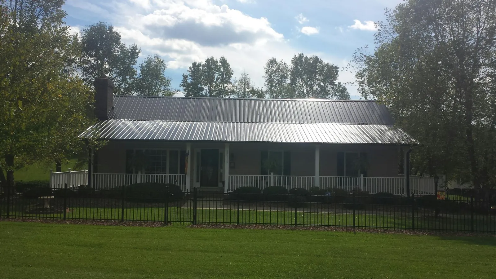 Gray metal roof on a brick ranch with a full width front porch — Gutter Guard Installation work by our crew in Arcanum