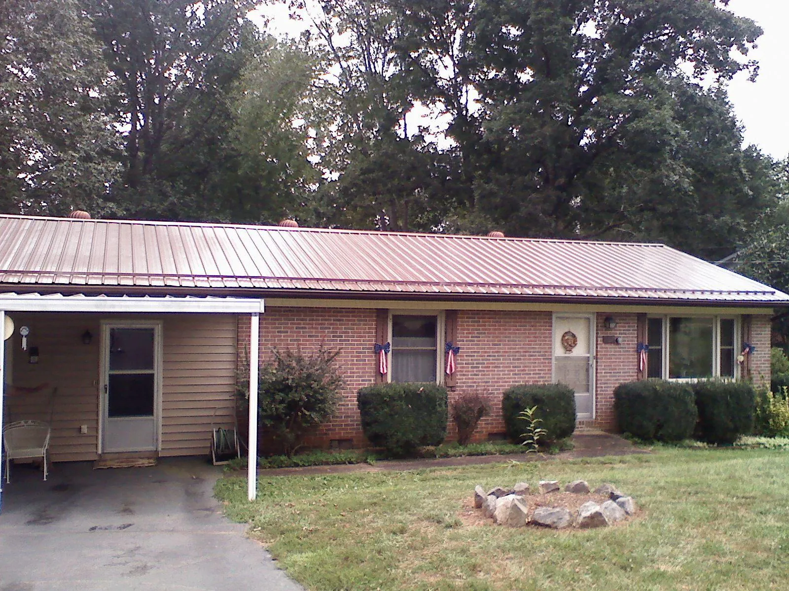 Bronze metal roof and carport on a brick ranch home — Roof Repair work by our crew in Arcanum